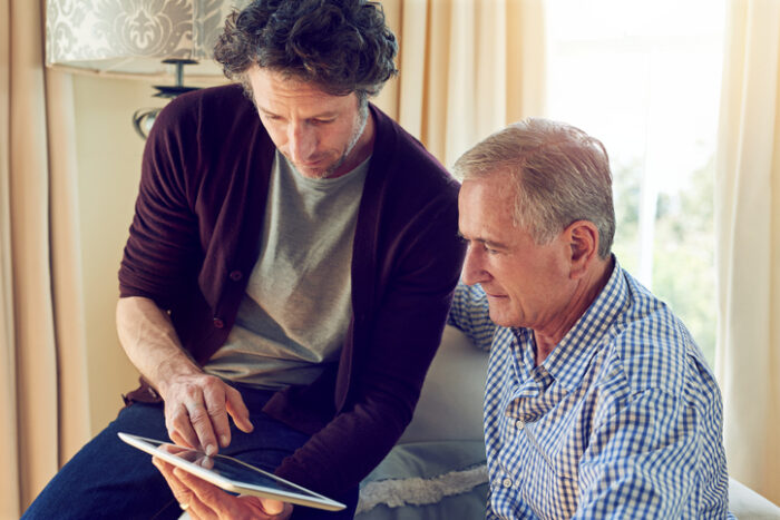 son showing his father how to use a tablet at home