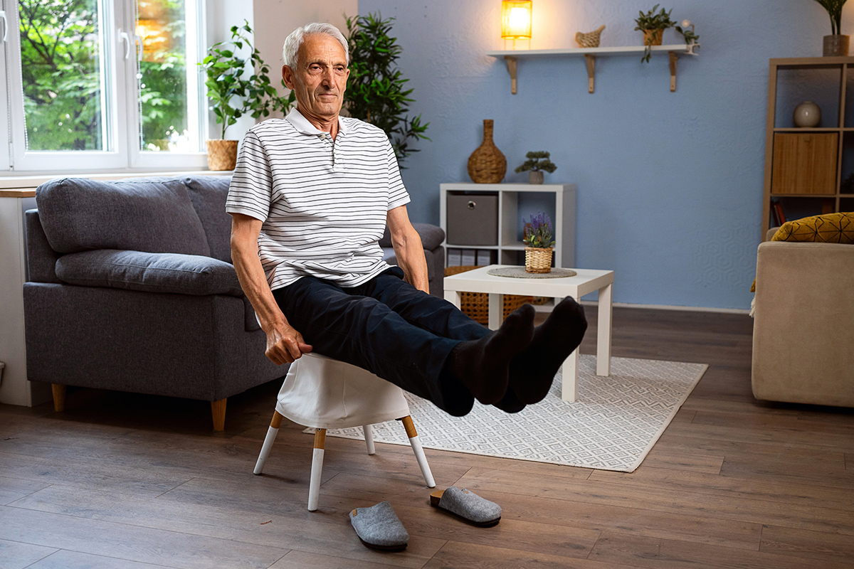 senior man doing seated leg lifts at home