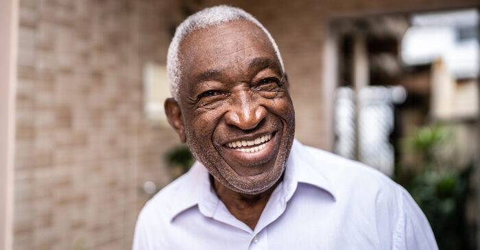 senior man smiling outside his home