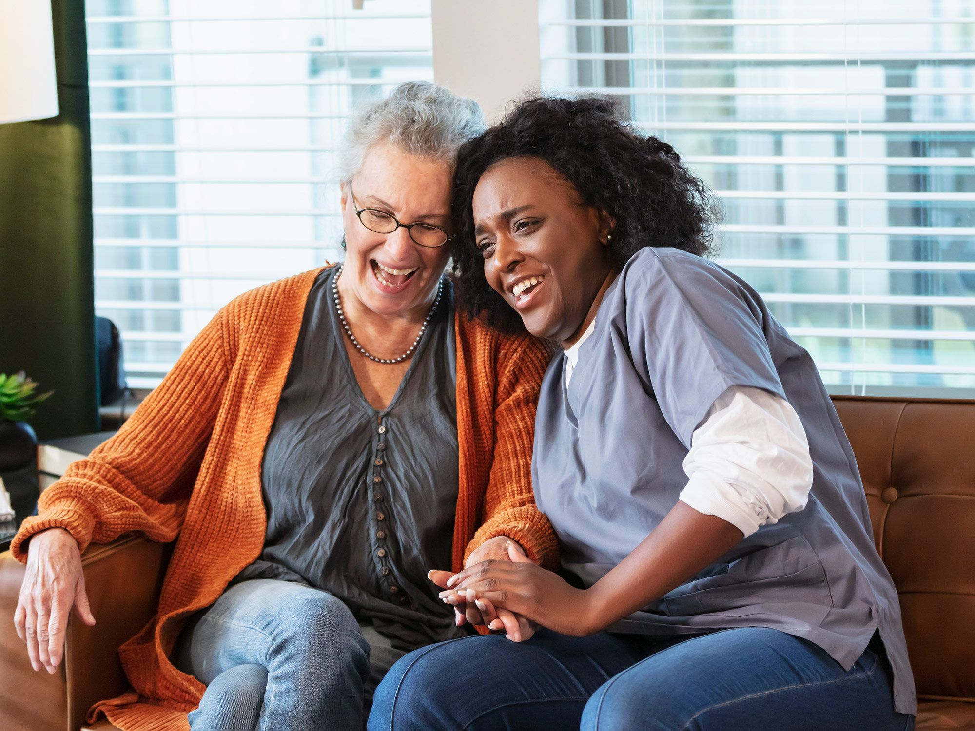 Senior and her caregiver laughing on the couch 