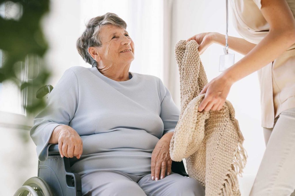 caregiver giving a senior a blanket