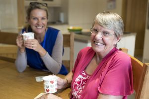 senior and caregiver having coffee together