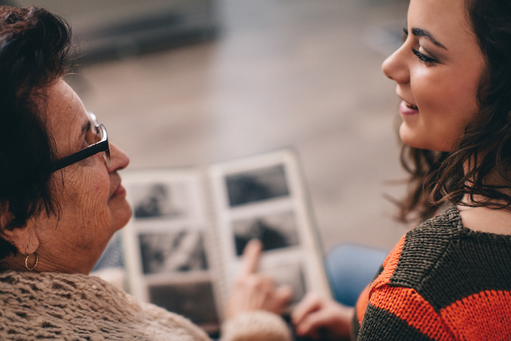 senior woman showing her granddaughter a photo album