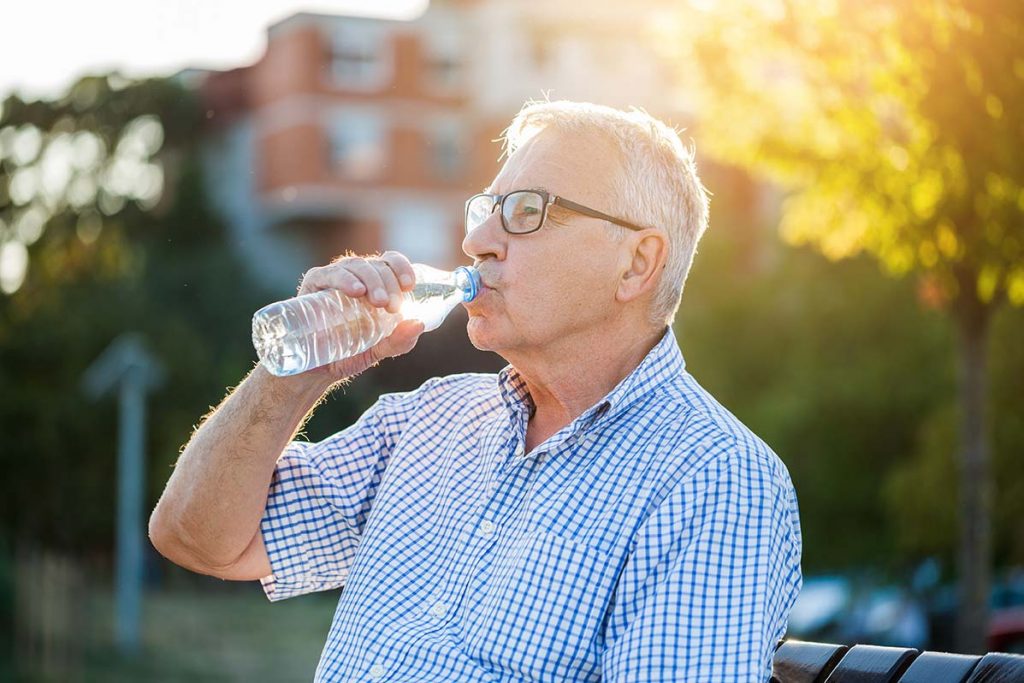 Elderly man enjoying the summer sun while staying hydrated by tracking his water intake.