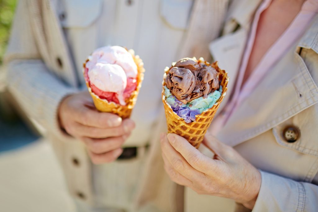 two seniors enjoying soft serve ice cream cones outside while enjoying the autumn breeze