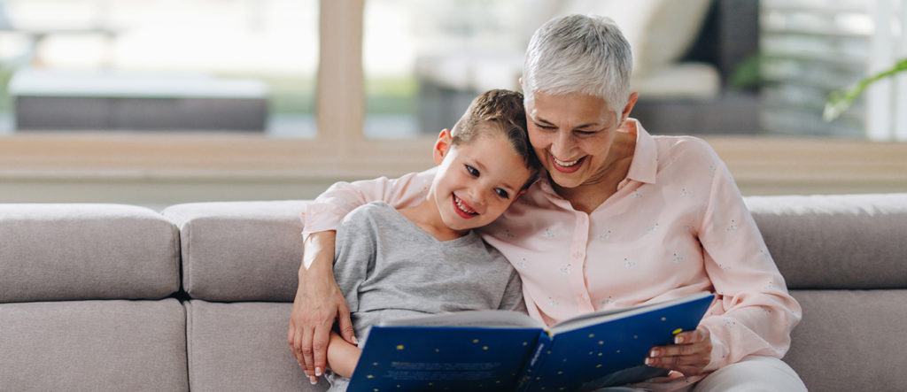 Senior and grandchild reading a book together