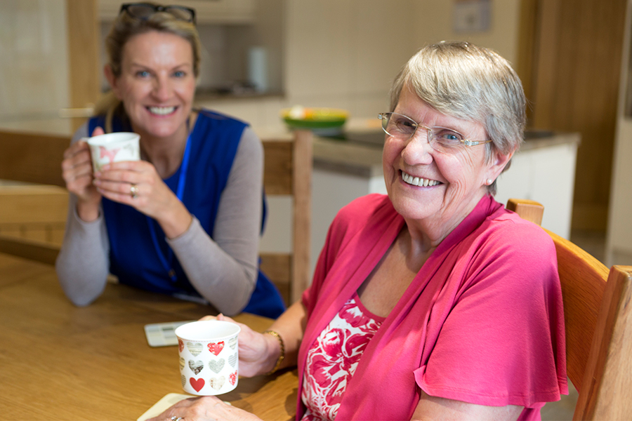 senior living caregiver and resident having coffee