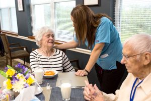 Elder woman and employee around breakfast table