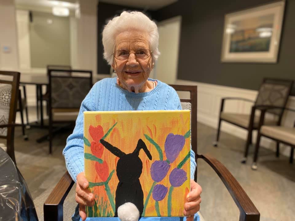 resident holding her painting she made at a community event