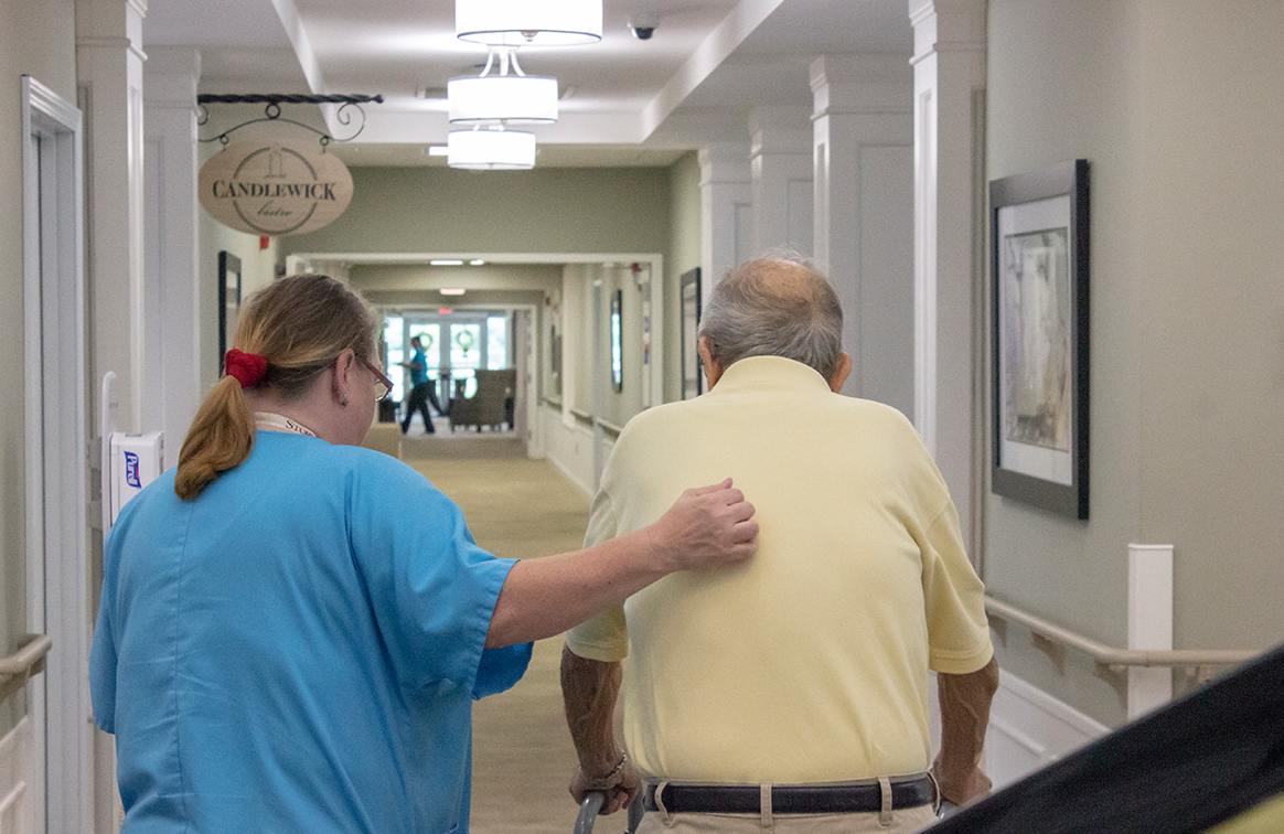 storypoint care staff member caring for a resident by walking with the resident to his apartment