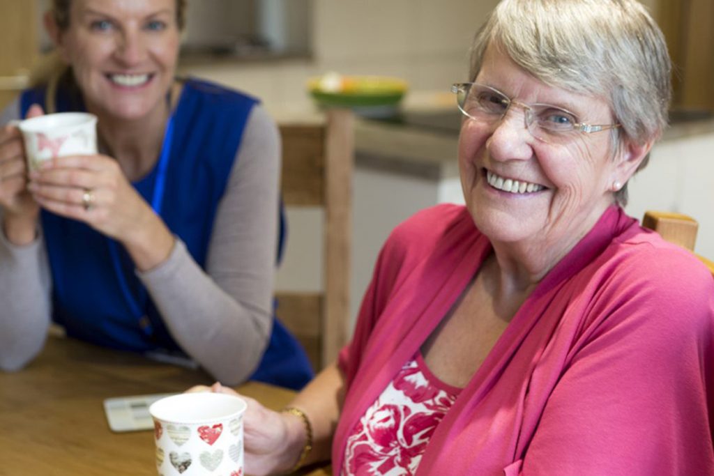 assisted living resident drinking coffee and asking common assisted living questions to a team member