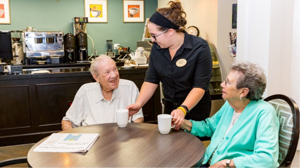 senior living dining employee serving coffee to residents