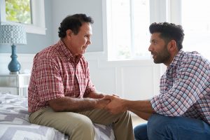 Father and Son holding hands on a bed