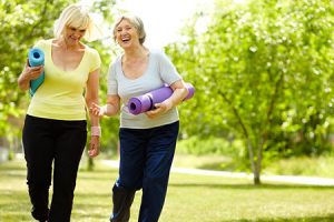 two women walking outside with yoga mats