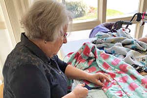 senior living resident making a blanket for project Linus