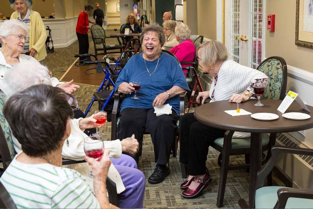 Independence Village residents laughing and enjoying refreshments at a community happy hour.