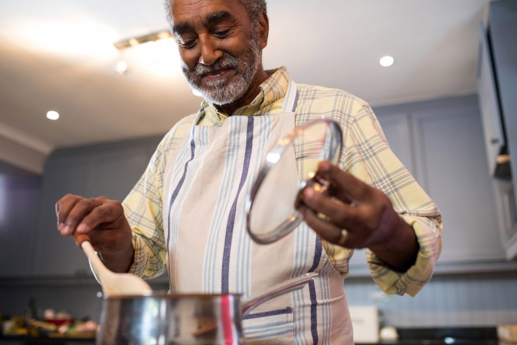 senior man cooking himself dinner while practicing senior kitchen safety tips