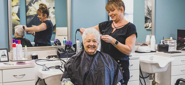 senior living resident getting her hair styled