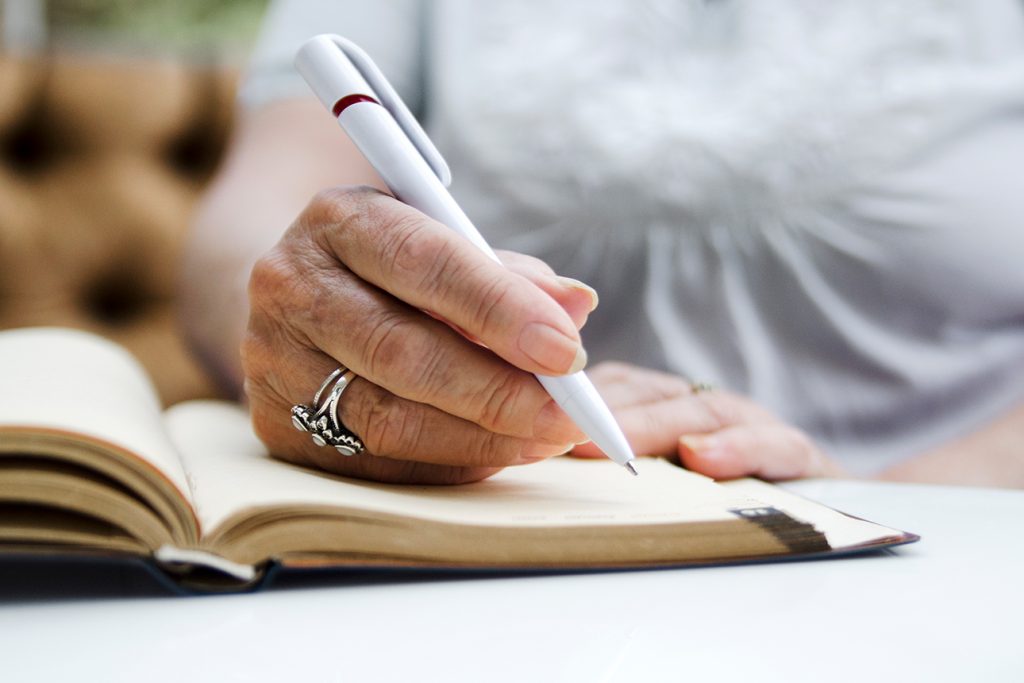 elderly woman writing in her notebook