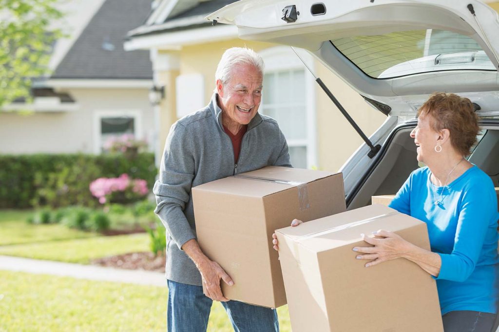 senior couple packing moving boxes into the trunk of the car