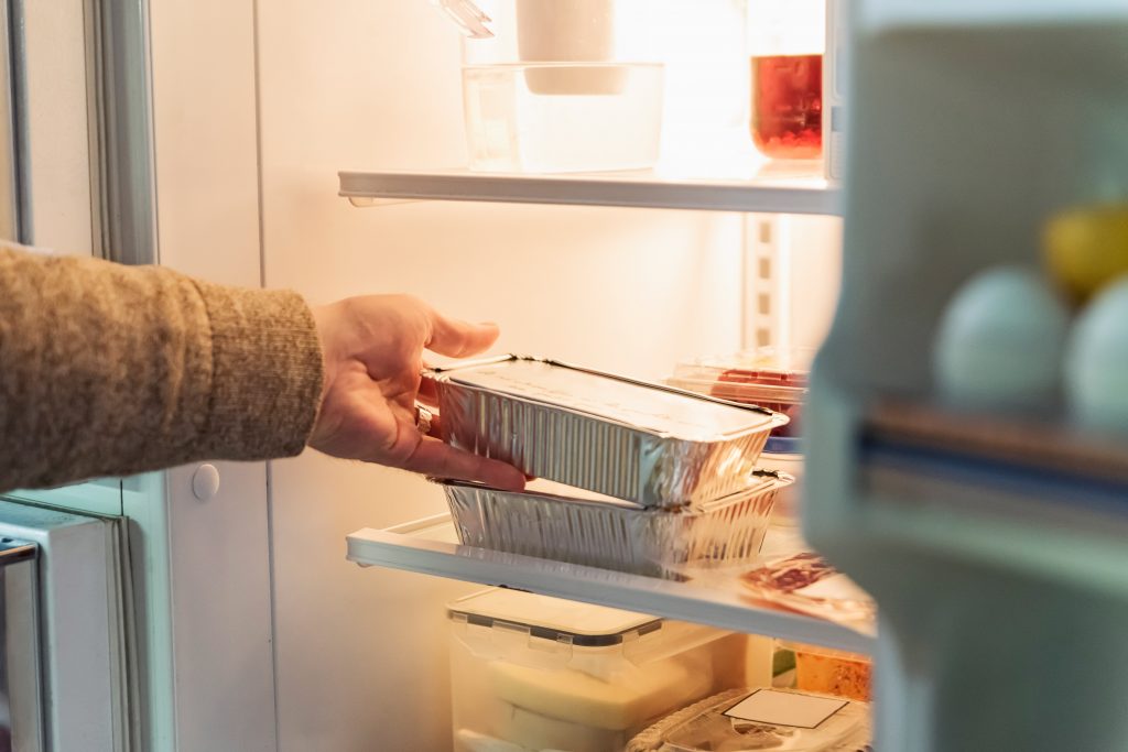 senior reaching for leftovers in the refrigerator 