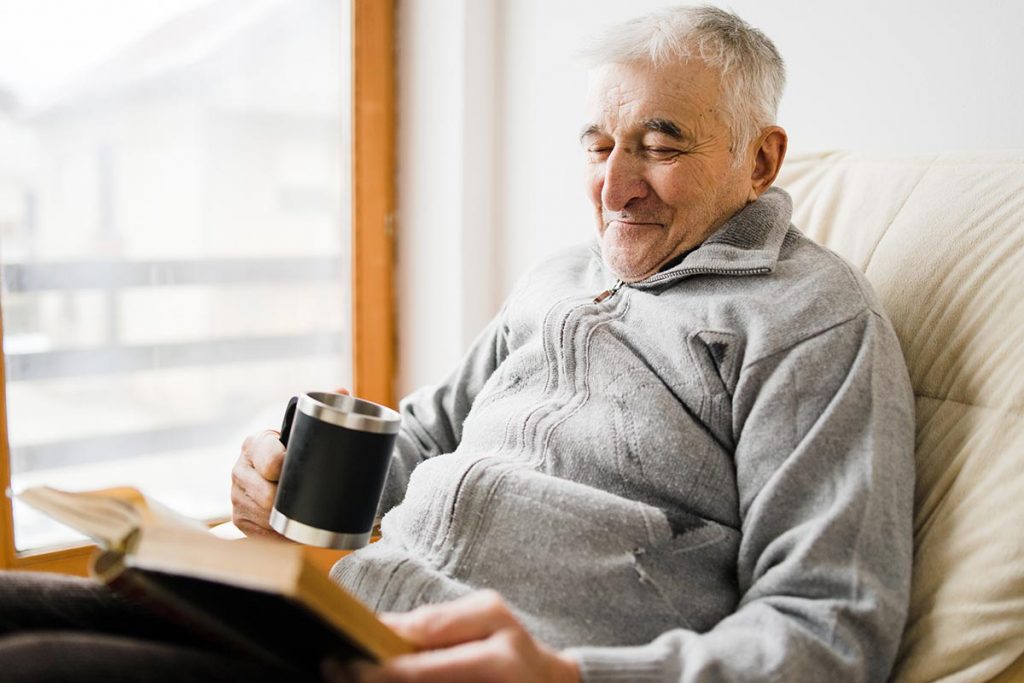 senior reading and drinking coffee