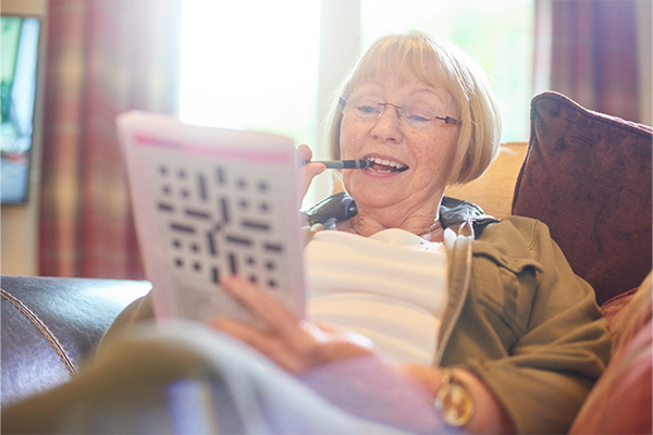 senior woman laying down playing crossword puzzle word association game