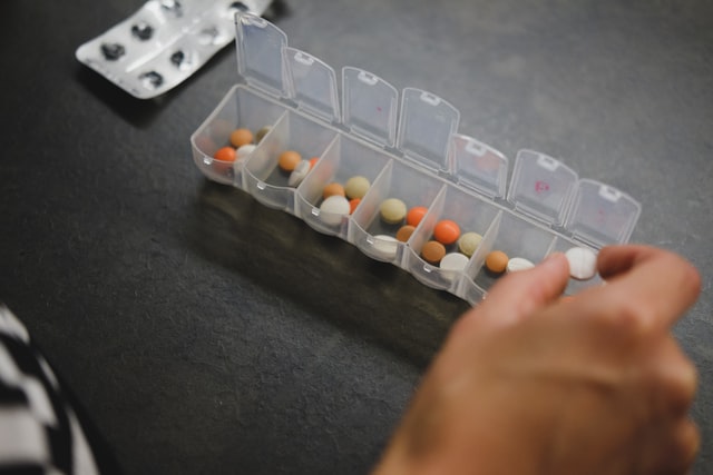 woman placing pills into pill holder