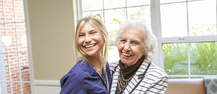 senior woman and young caregiver laughing