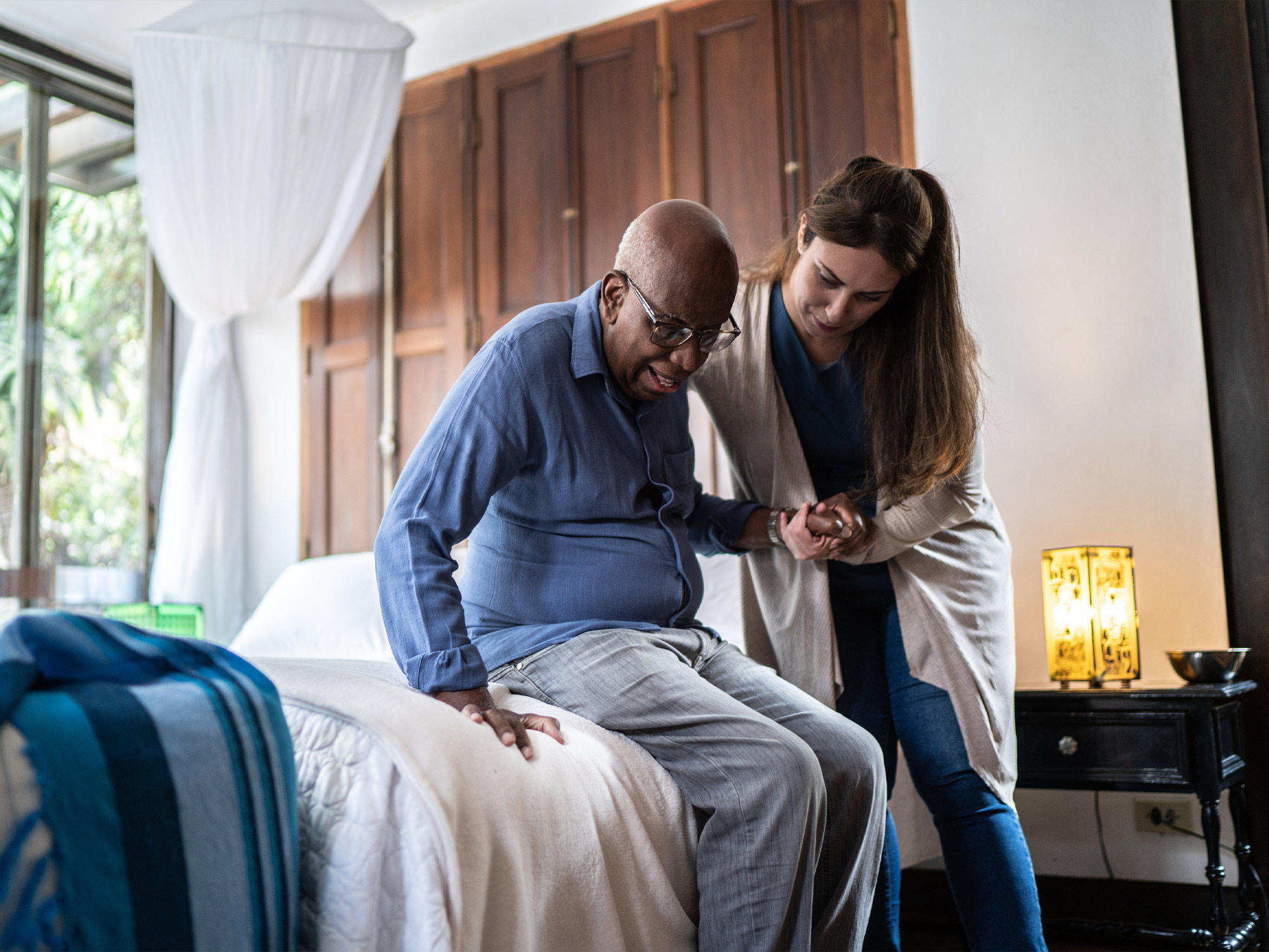 caregiver helping a senior out of bed