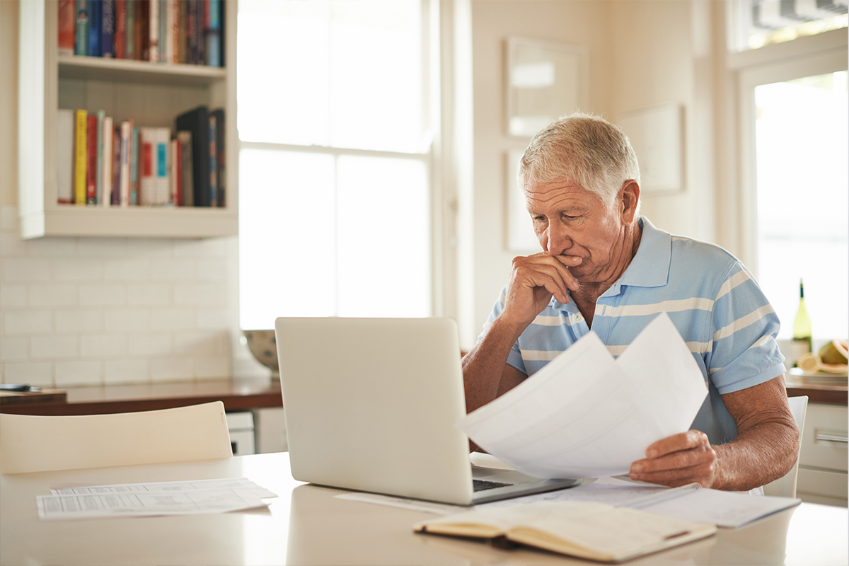 Senior looking at paperwork and a laptop