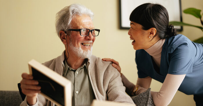 senior and a caregiver reading a book