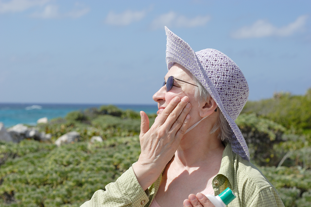 senior woman applying sunscreen