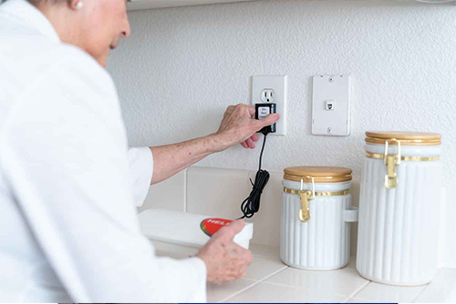 senior plugging in the Bay Alarm SOS All-In-One With Fall Detection device