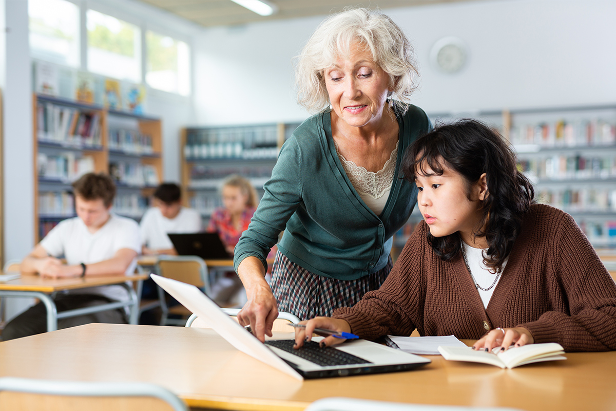 Senior woman tutoring a girl at the library