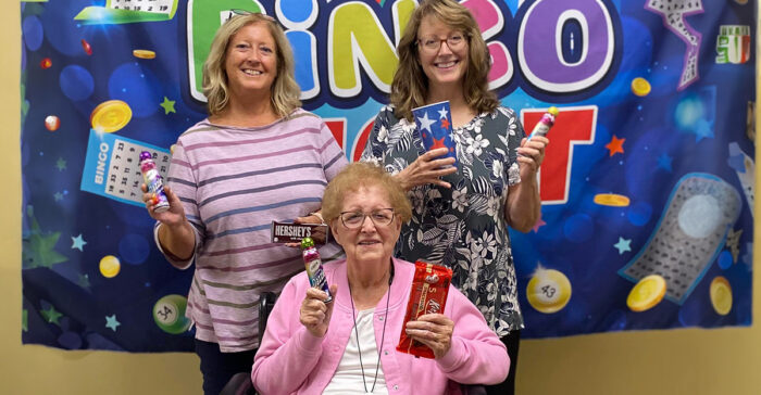 Senior and visitors showing off their bingo prizes