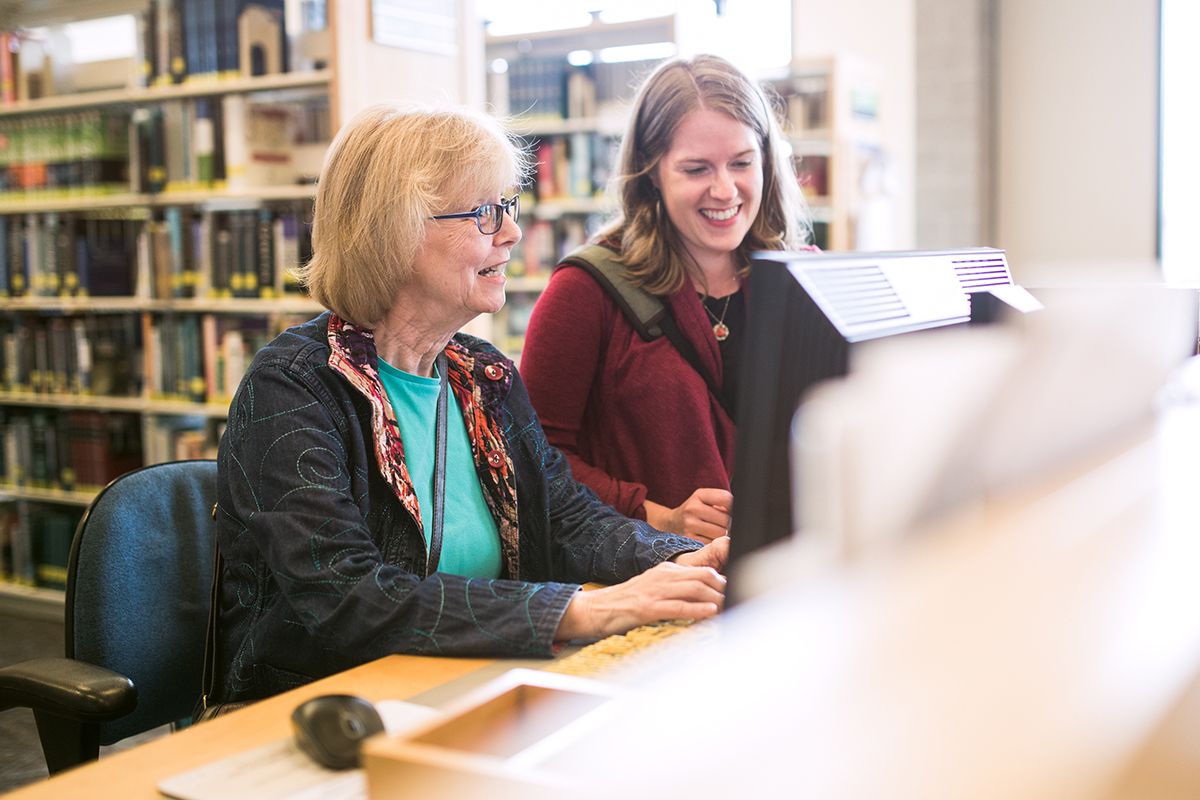 woman and senior at the library computer