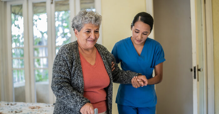 senior woman walking with the help of a caregiver