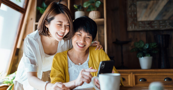 Senior woman and her adult child using a smartphone together.