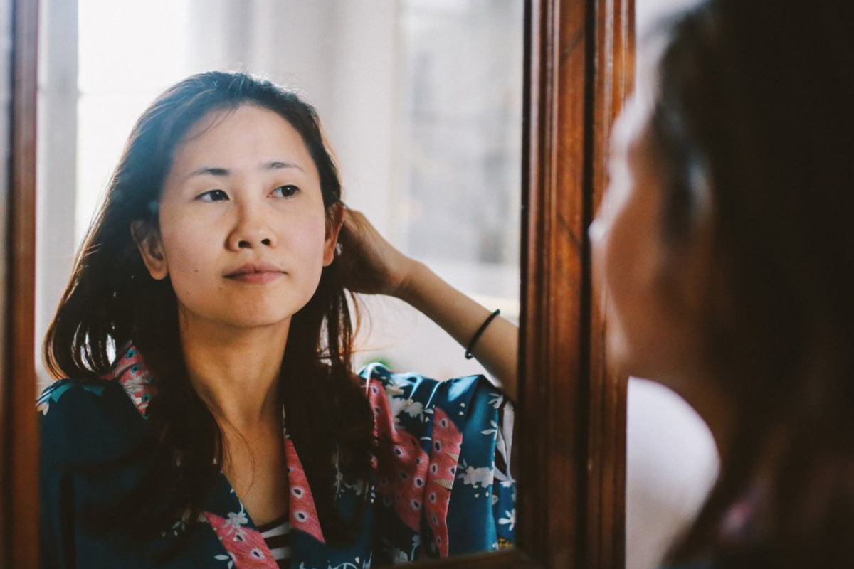 A woman looking at her reflection in a mirror.