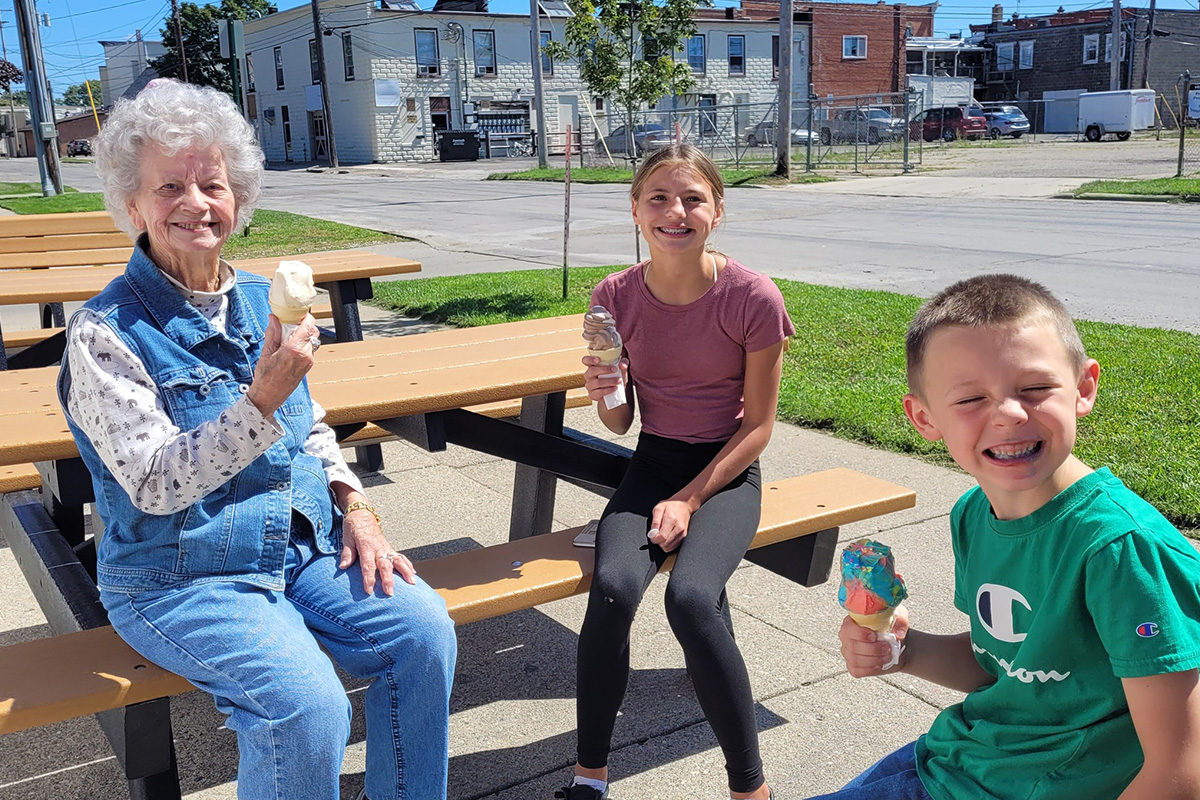 Oliver Woods resident and her grandchildren eating ice cream outside at a picnic table. 