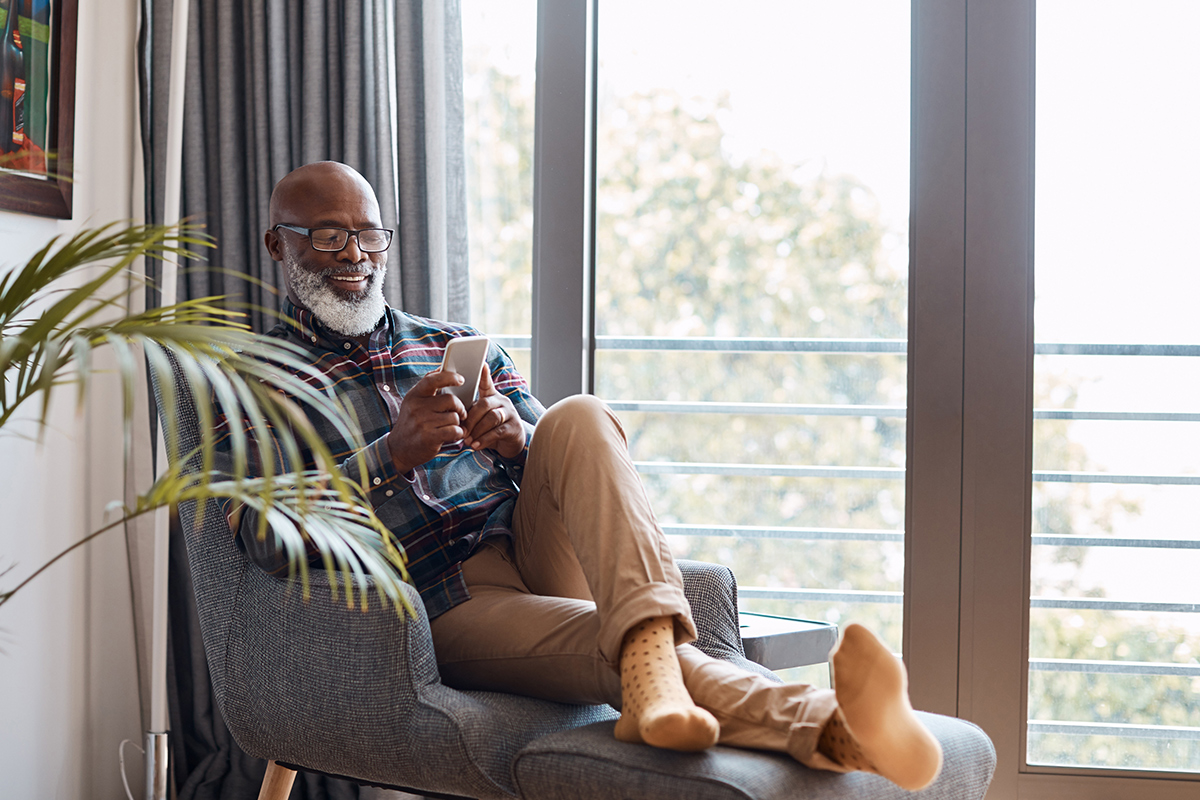 Senior man smiling while using a smart phone.