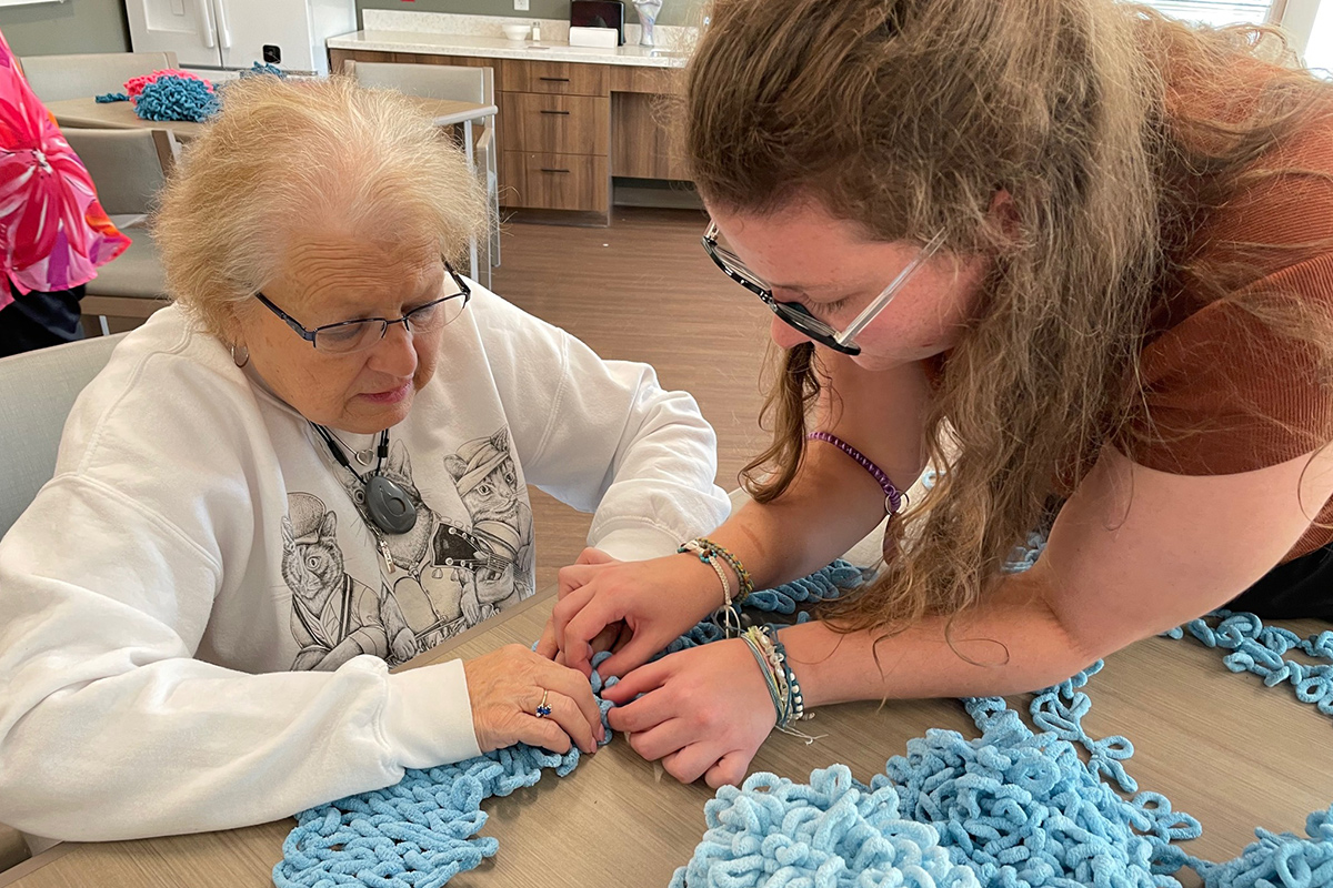 StoryPoint resident crocheting with a caregiver 