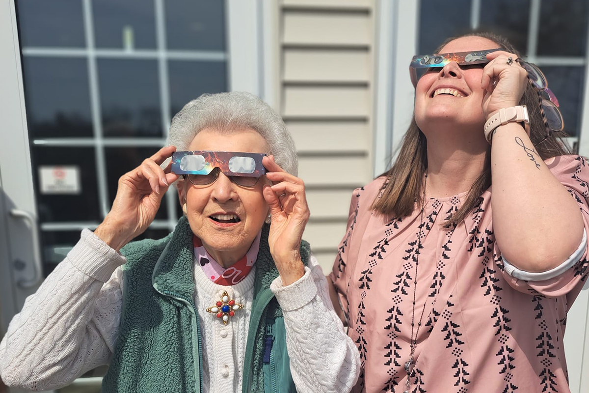 StoryPoint resident and caregiver looking at the solar eclipse 