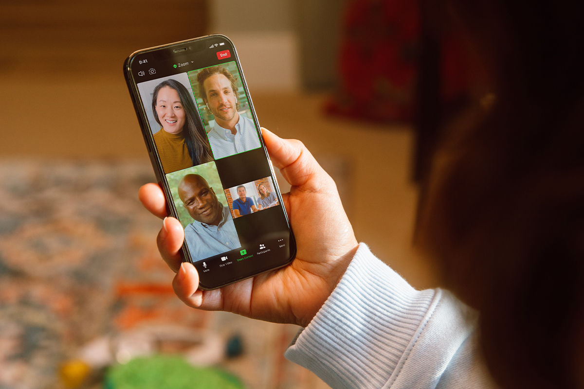 A smartphone showing the Zoom app, with four participants currently on the call.