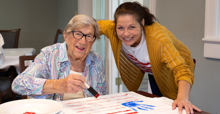 StoryPoint resident and caregiver painting a patriotic craft.