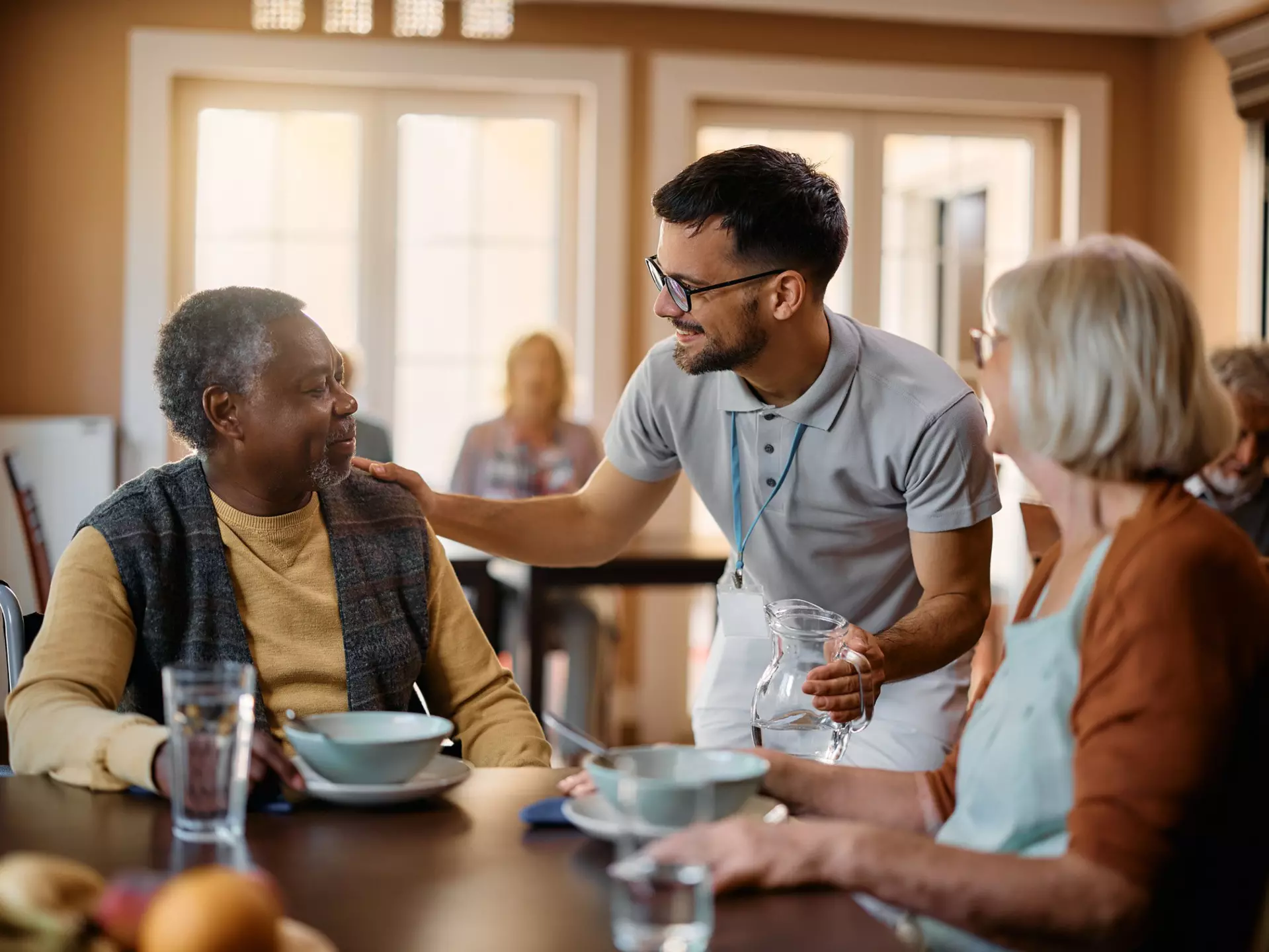 Seniors are being served breakfast in a community dining room.