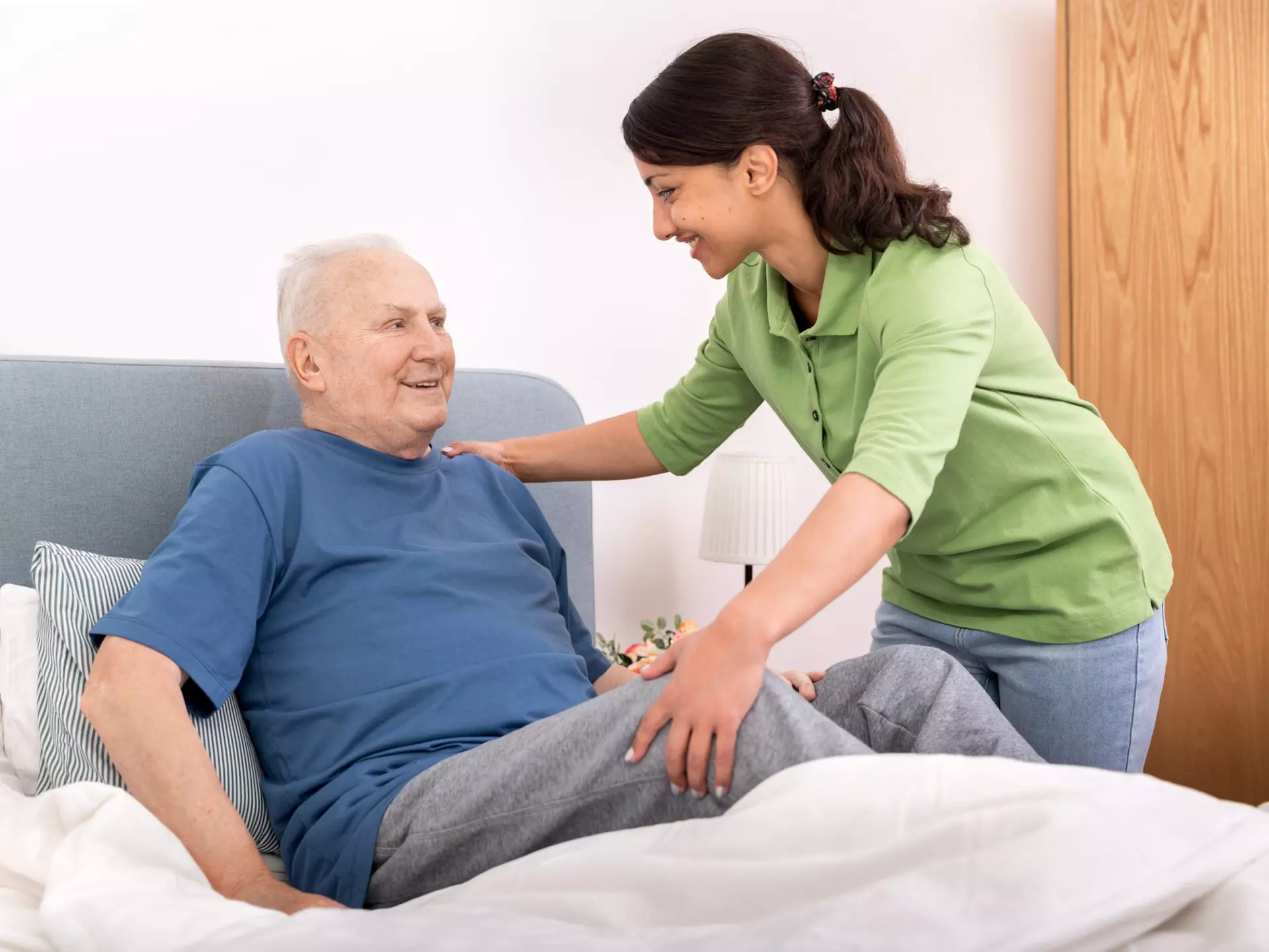 A caregiver is assisting an older gentleman with transferring from bed.