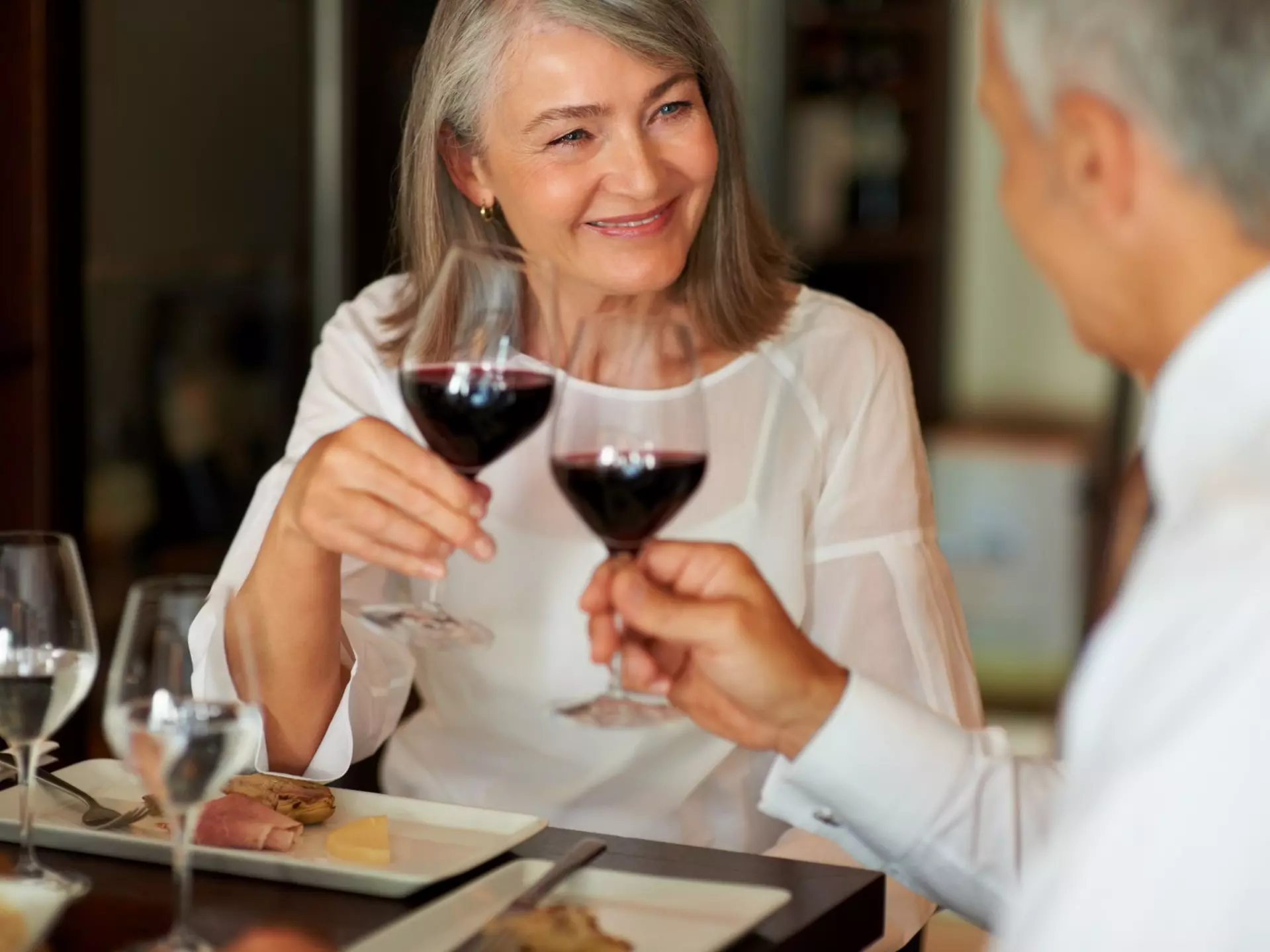 A senior couple making a toast with their wine glasses.