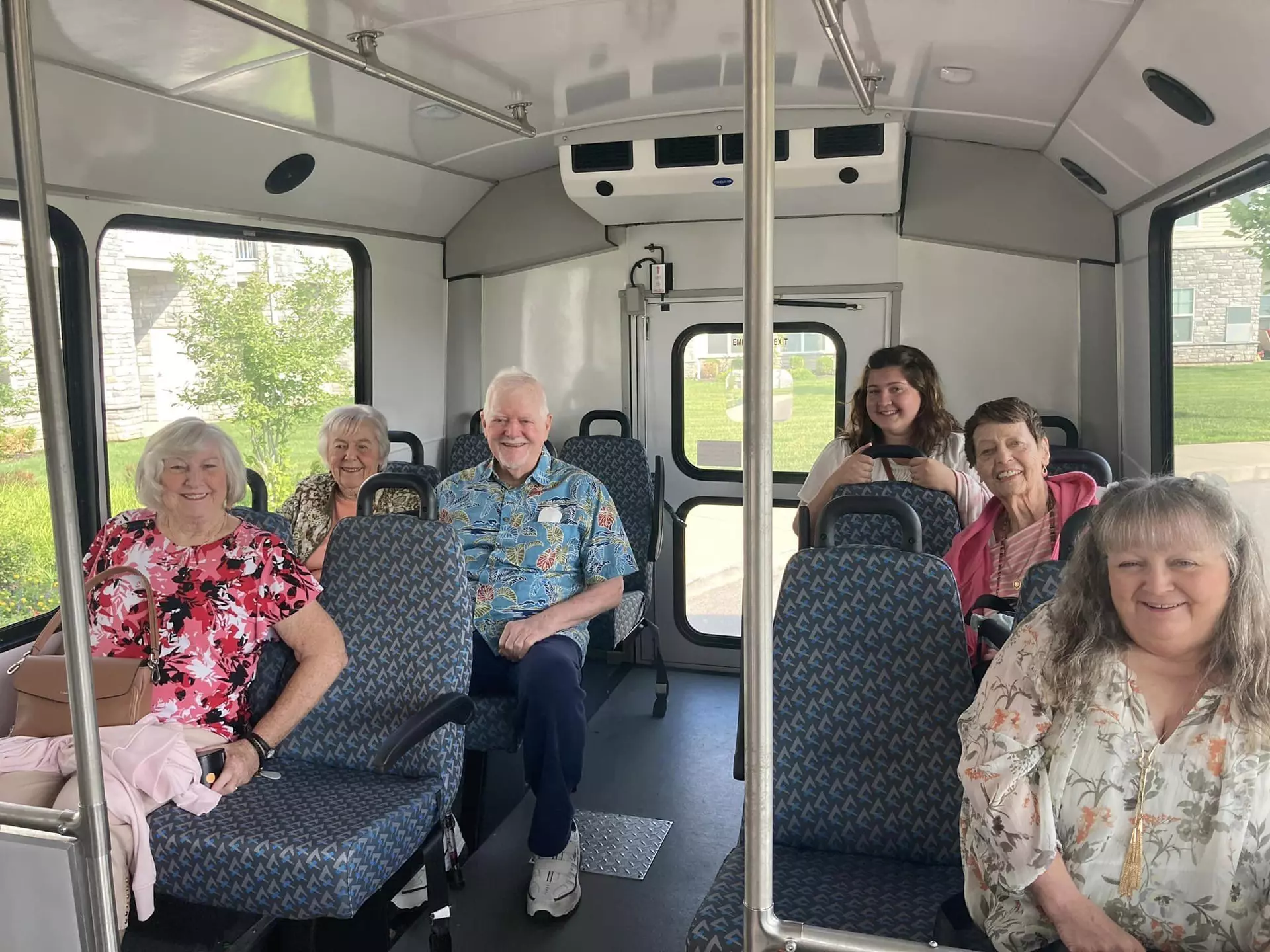 A group of joyful seniors seated in a bus.